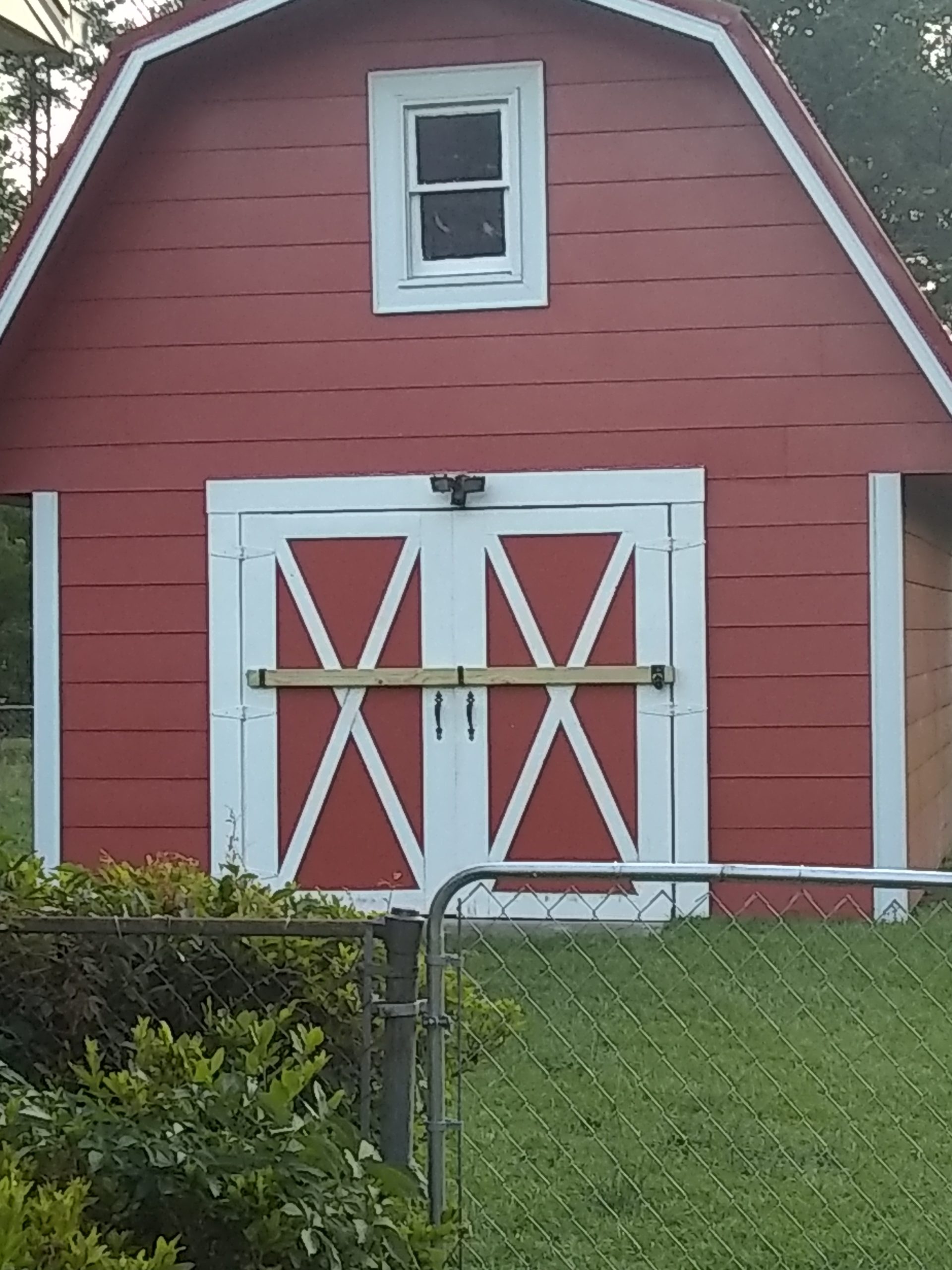 Red gable roofed barn with secure 2x4 bar holders with lock