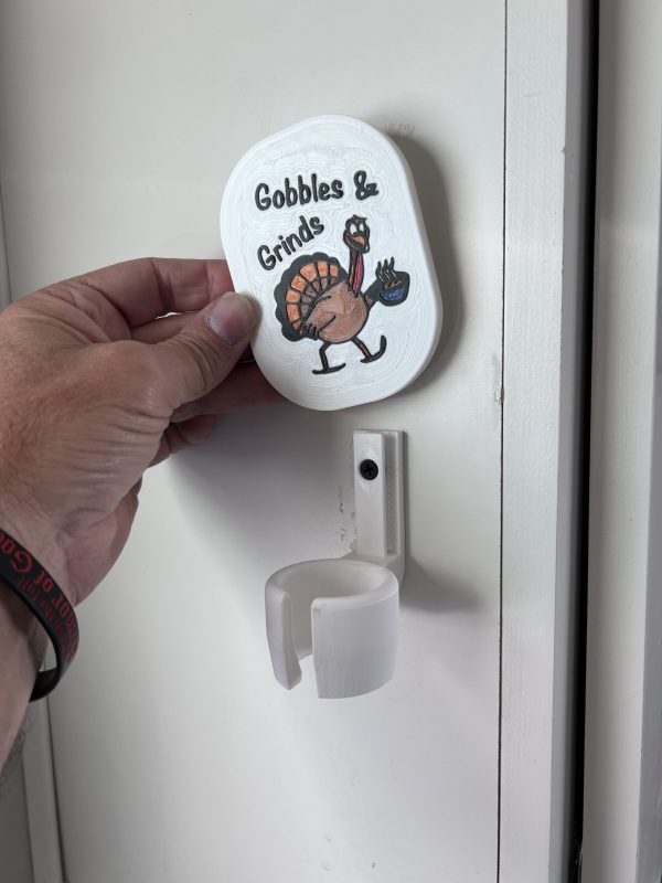 Cute Gobble and Grinds Thanksgiving Holiday Faceplate for Milk Frother Stand Only for Wall Mount - Shown on Cabinet placing faceplate on mounting bracket